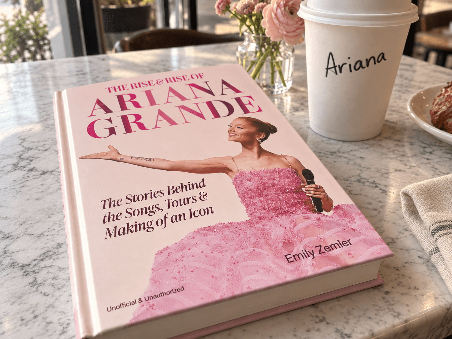 Ariana Grande book on a café table beside a to-go coffee cup with "Ariana" written on it